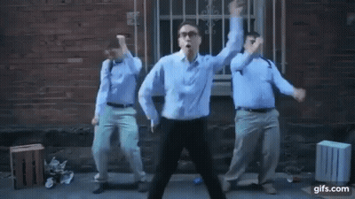 Three Men Are Dancing In Front Of A Brick Building . GIF