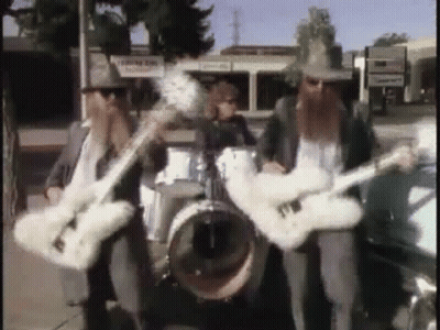 Three Men Are Playing Guitars And Drums In A Band On A Sidewalk . GIF