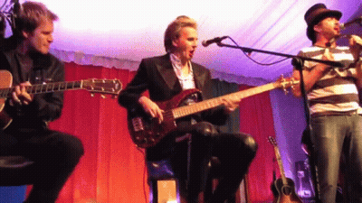 Three Men Are Playing Guitars And Singing Into Microphones GIF