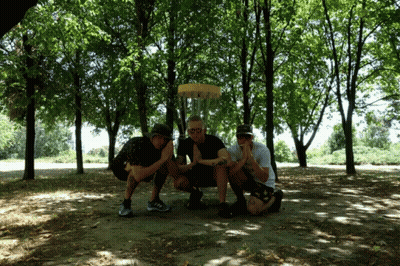 Three Men Are Posing For A Picture In Front Of A Frisbee GIF