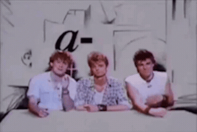 Three Men Are Sitting At A Table And Talking To Each Other . GIF