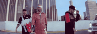 Three Men Are Standing In Front Of A Building And One Of Them Is Wearing A Jacket That Says Supreme GIF