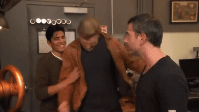 Three Men Are Standing In Front Of A Door That Has A Fire Extinguisher Sign On It GIF