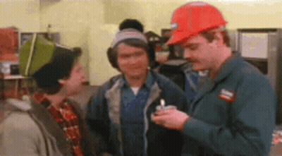 Three Men Are Standing Next To Each Other In A Room . One Of The Men Is Wearing A Hard Hat . GIF