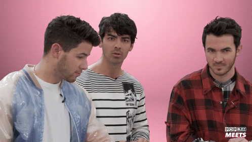 Three Men Are Standing Next To Each Other In Front Of A Pink Background That Says Pop Blitz Meets On It GIF