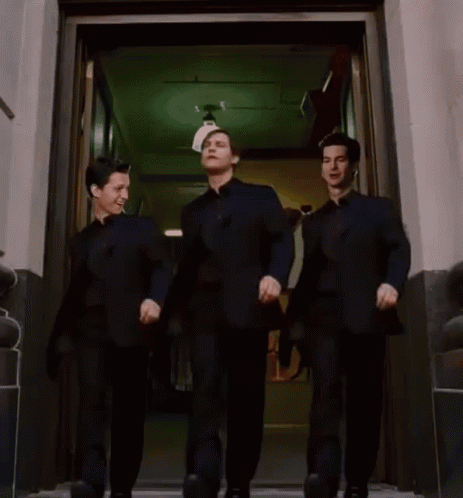 Three Men In Black Suits Are Walking Out Of A Doorway GIF