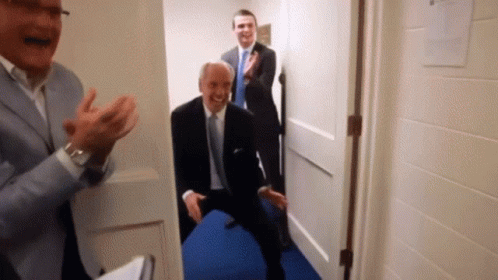 Three Men In Suits And Ties Are Standing In A Hallway Clapping GIF