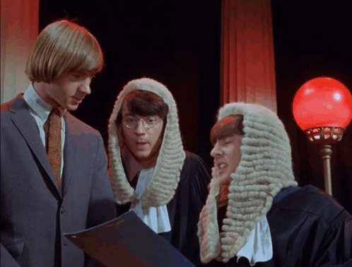 Three Men In Wigs Are Looking At A Book GIF