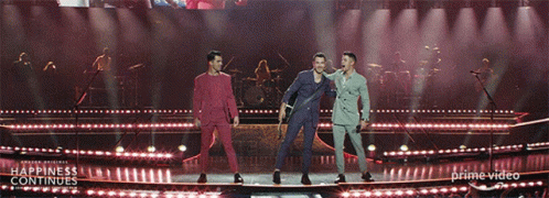 Three Men On A Stage With The Words Happiness Continues On The Bottom Right GIF