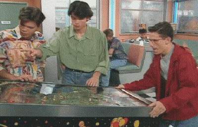Three Men Playing Pinball Machine In Diner With TNT Sign GIF