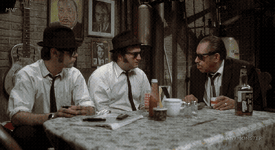 Three Men Sitting At Table With Giant Monster Logo GIF