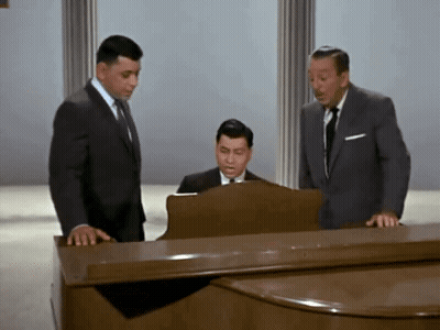 Three Men Standing Around Piano One Playing GIF