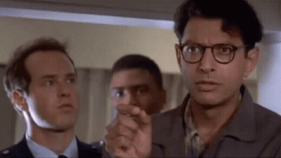 Three Men Standing, One Pointing At Camera GIF