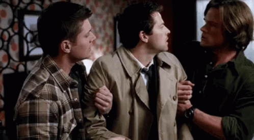 Three Men Standing Together One Holding Arm GIF