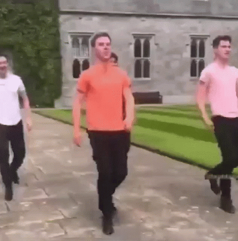 Three Men Walking Past Large Building GIF
