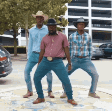 Three Men Wearing Cowboy Hats And Jeans Are Dancing In A Parking Lot GIF