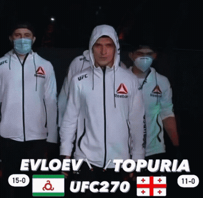 Three Men Wearing Face Masks And Reebok Jackets Are Standing In Front Of A Scoreboard For Ufc 270 GIF