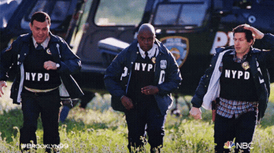 Three NYPD Officers Walking In Field With Helicopter GIF