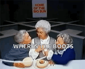 Three Older Women Are Sitting At A Table With A Sign That Says `` Home Of The Big Bun '' Behind Them . GIF