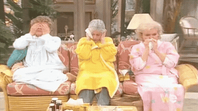 Three Older Women Are Sitting On A Couch Blowing Their Noses With Tissues . GIF