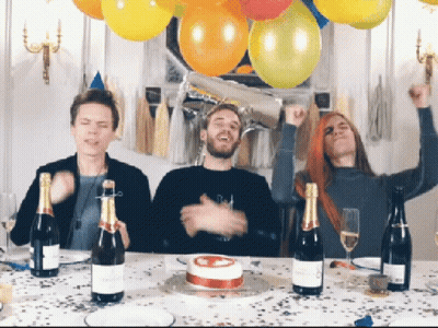 Three People Are Sitting At A Table With Bottles Of Champagne And A Birthday Cake GIF