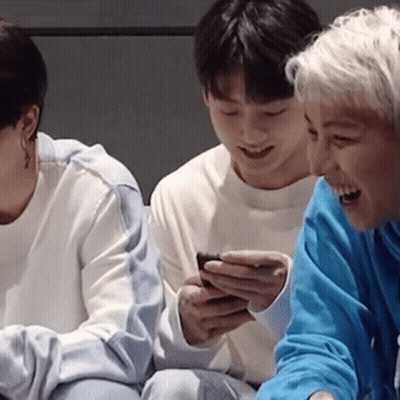 Three People Are Sitting Next To Each Other And One Of Them Is Holding A Cell Phone . GIF