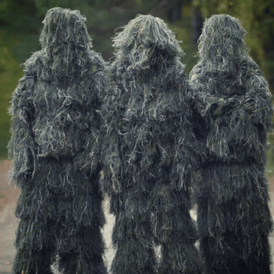 Three People Dressed In Sniper Suits Are Standing In A Line GIF