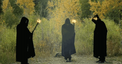 Three People In Black Cloaks Holding Torches GIF