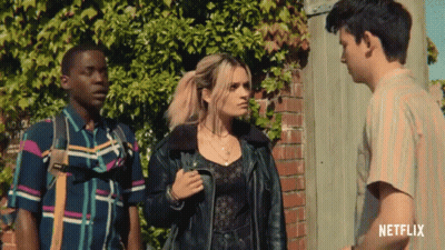 Three People Standing In Front Of A Brick Wall With A Netflix Logo On The Bottom Right GIF