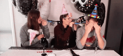 Three People Wearing Party Hats Blowing Party Horns GIF