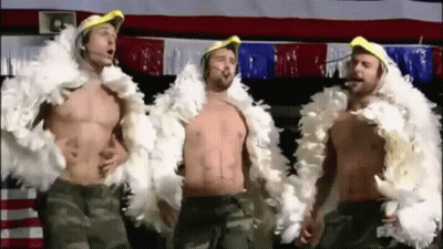 Three Shirtless Men Are Standing Next To Each Other Wearing Feather Boa Jackets . GIF