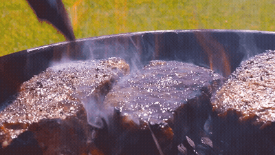 Three Steaks Cooking On A Grill With Smoke GIF