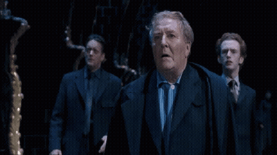 Three Suited Men In Dark Room, One Surprised GIF