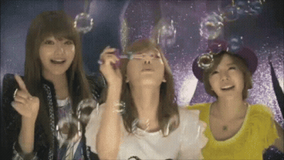 Three Women Are Blowing Soap Bubbles In Front Of A Starry Sky . GIF