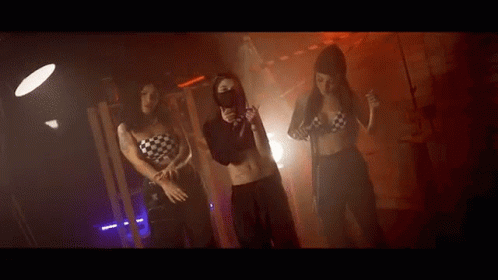 Three Women Are Dancing Together In A Dark Room . GIF