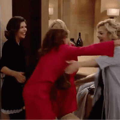 Three Women Are Hugging Each Other In A Room . One Of The Women Is Wearing A Red Dress . GIF