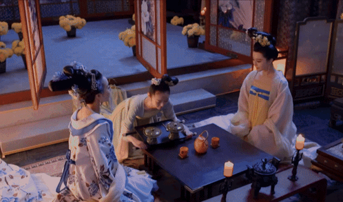 Three Women Are Sitting At A Table With Candles GIF
