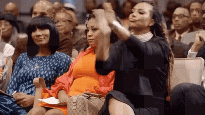 Three Women Are Sitting In A Crowd Of People And One Of Them Is Taking A Picture Of Herself With Her Phone . GIF