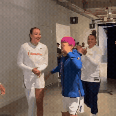 Three Women Are Standing In A Locker Room And One Of Them Is Wearing A White Shirt With The Word Basketball On It GIF