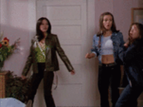 Three Women Are Standing In Front Of A White Door GIF