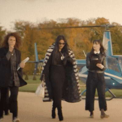 Three Women Are Walking Towards A Helicopter With The Letter E On Their Coat GIF