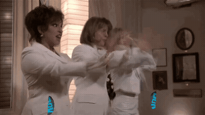Three Women In White Suits Standing In Living Room GIF