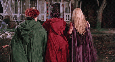 Three Women In Witch Costumes Walking Down Street GIF