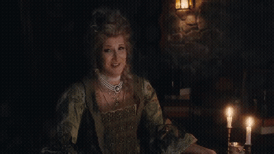 Three Women Laughing At Table In Dark Room GIF