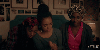 Three Women Sitting on Bed With Netflix Logo