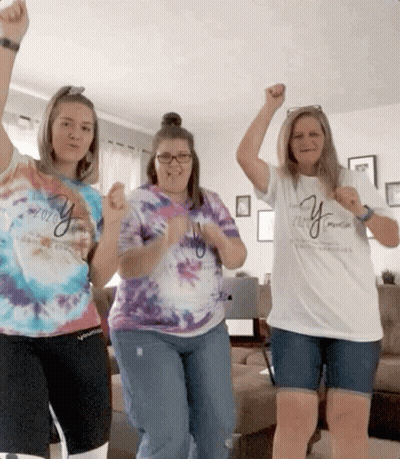 Three Women Wearing Tie Dye Shirts With The Word Young On Them Are Dancing In A Living Room GIF