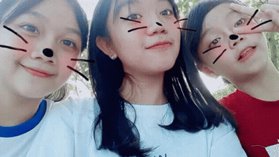 Three Young Girls Are Posing For A Picture Together And One Of Them Has A Cat Face Drawn On Her Face . GIF