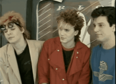 Three Young Men Standing In Front Of RL Poster GIF