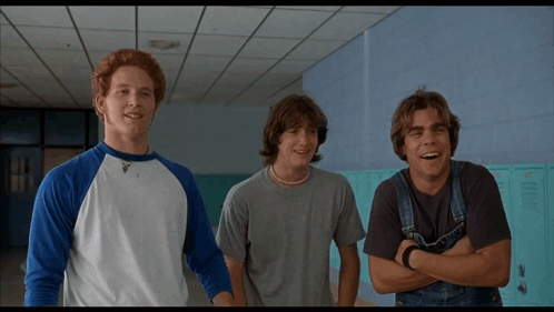 Three Young Men Standing Next To Each Other In A Hallway With Lockers In The Background GIF