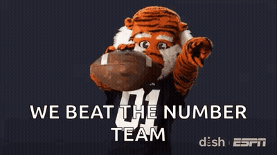 Tiger Mascot Holding Football Saying We Beat the Number Team